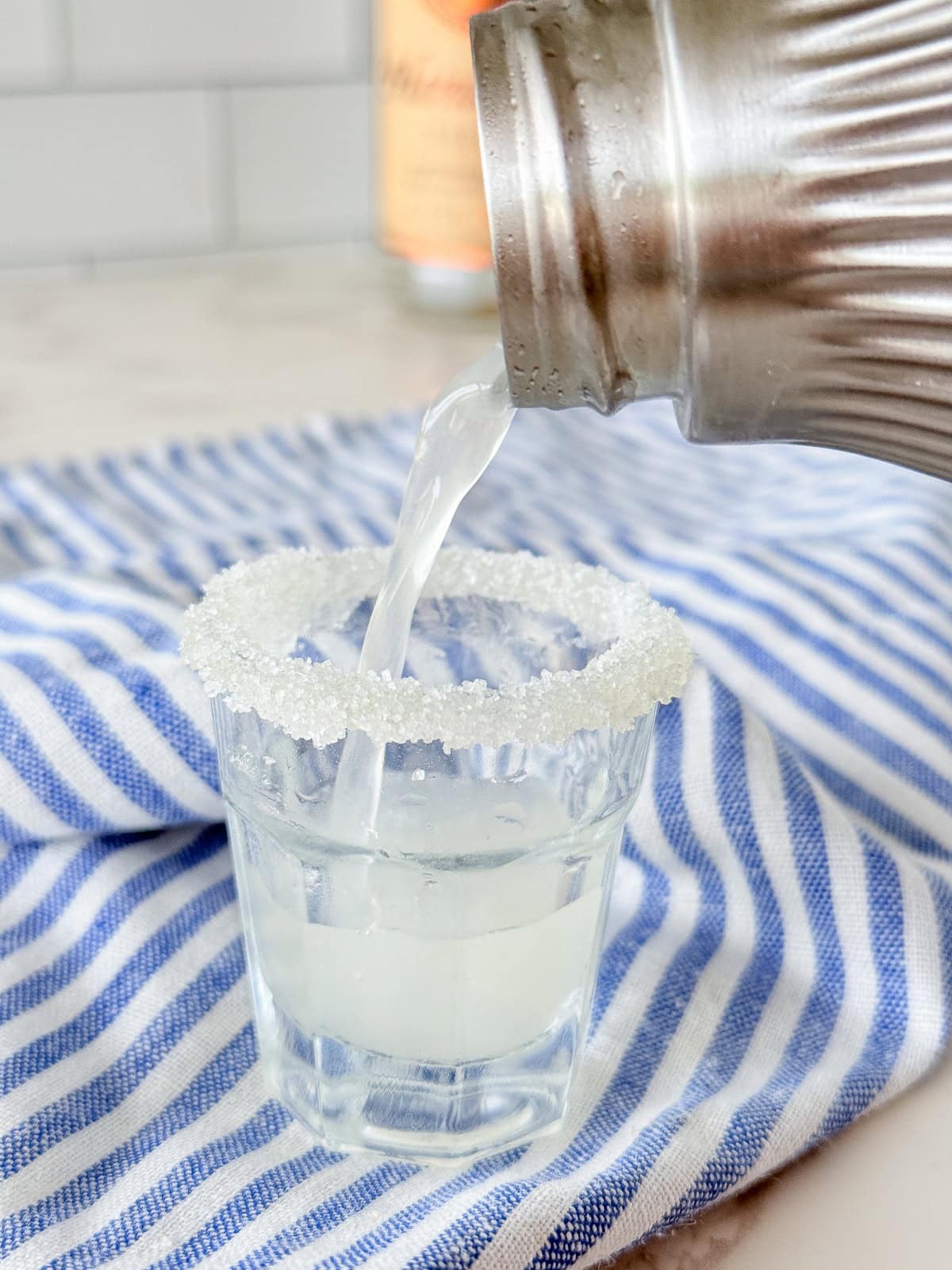 Pouring lemon drop shot into shot glass.