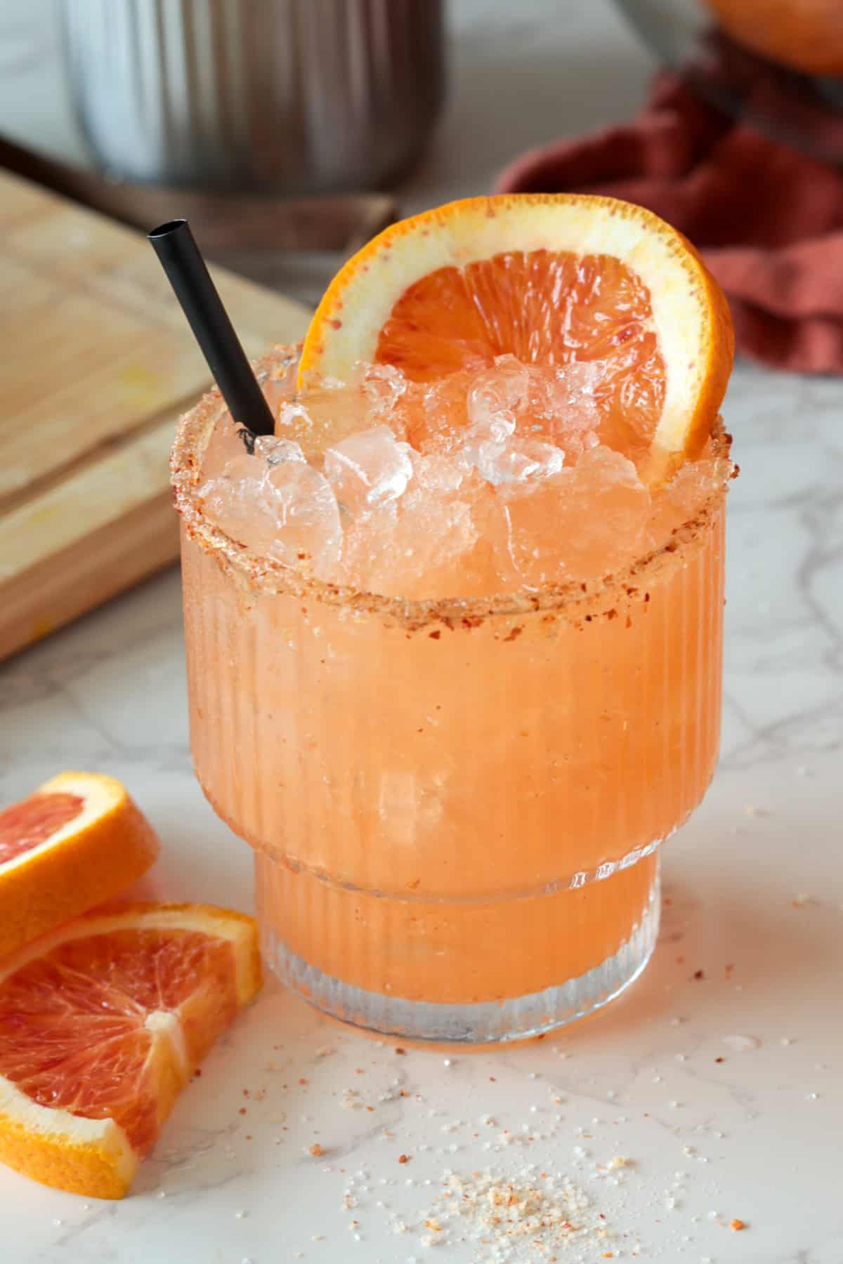 Blood orange margarita with blood orange slice and straw.