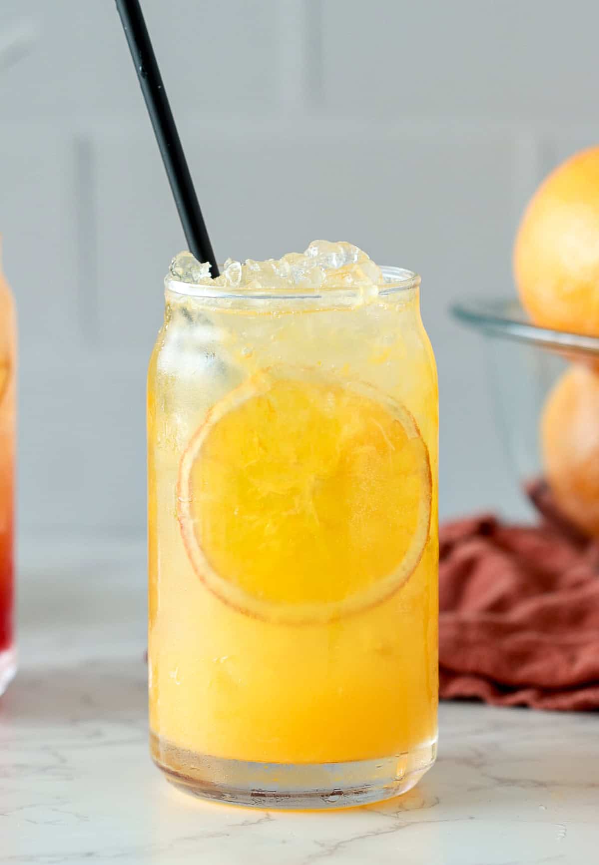Orange crush cocktail with black straw and orange slice.
