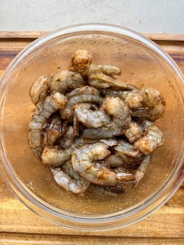 Raw shrimp in bowl with jerk seasoning.
