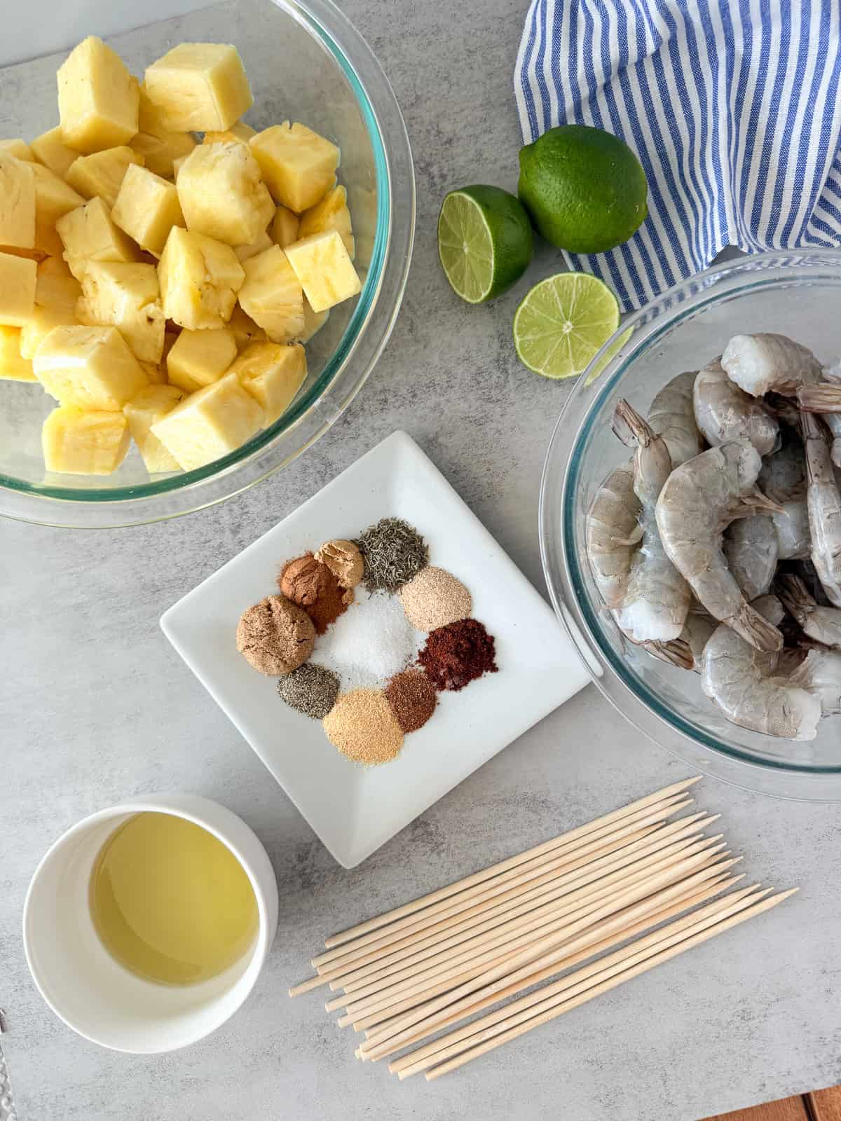 Shrimp pineapple skewer ingredients on table with wooden skewers.