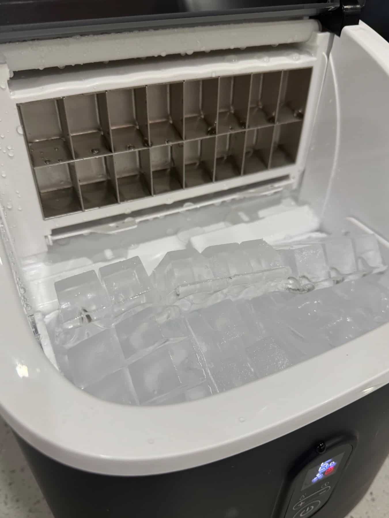 Fresh square ice cubes released in a connected sheet inside the COSTWAY countertop ice maker.