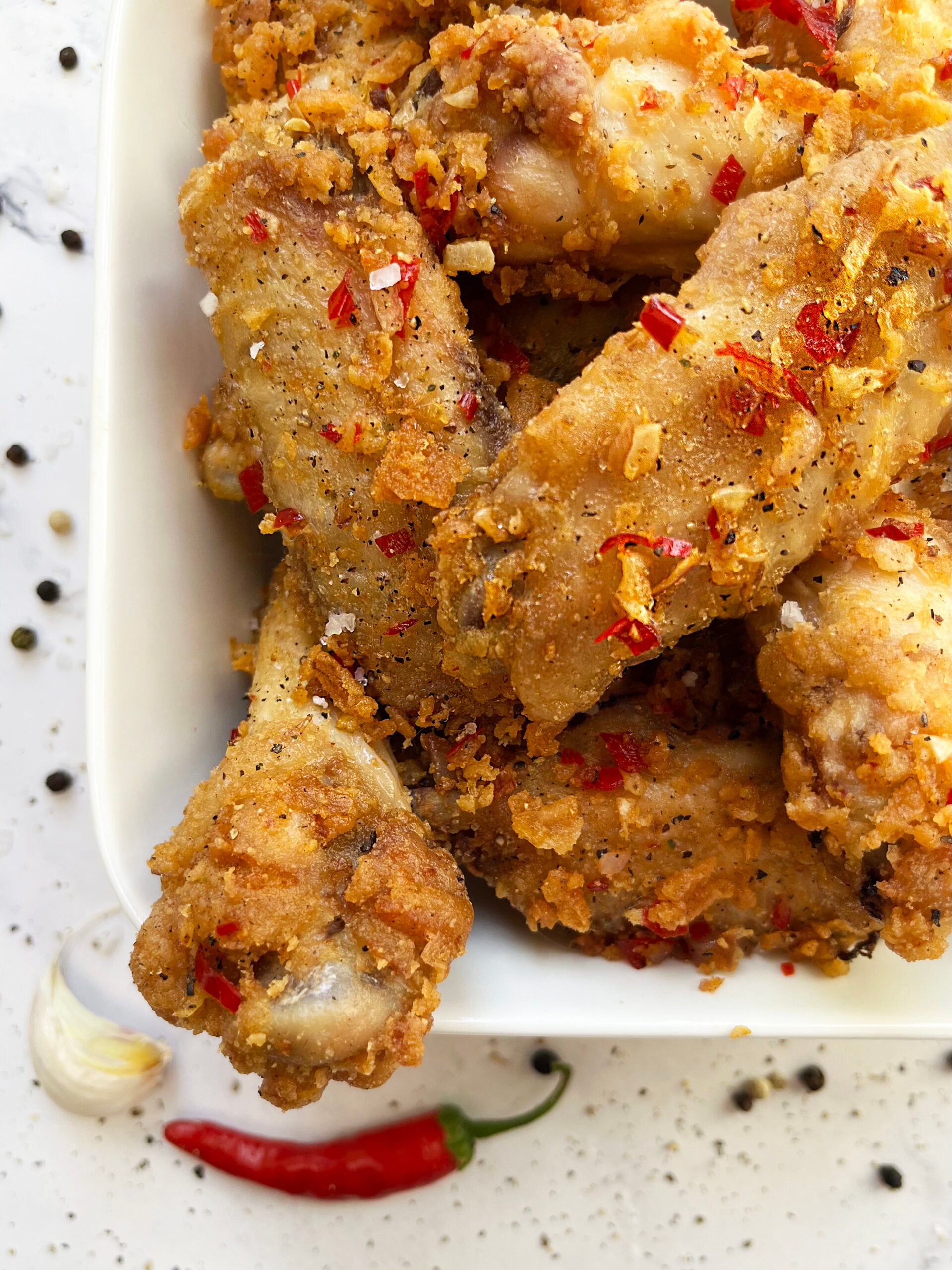 Close-up of crispy salt and pepper chicken wings with garlic and red chile.