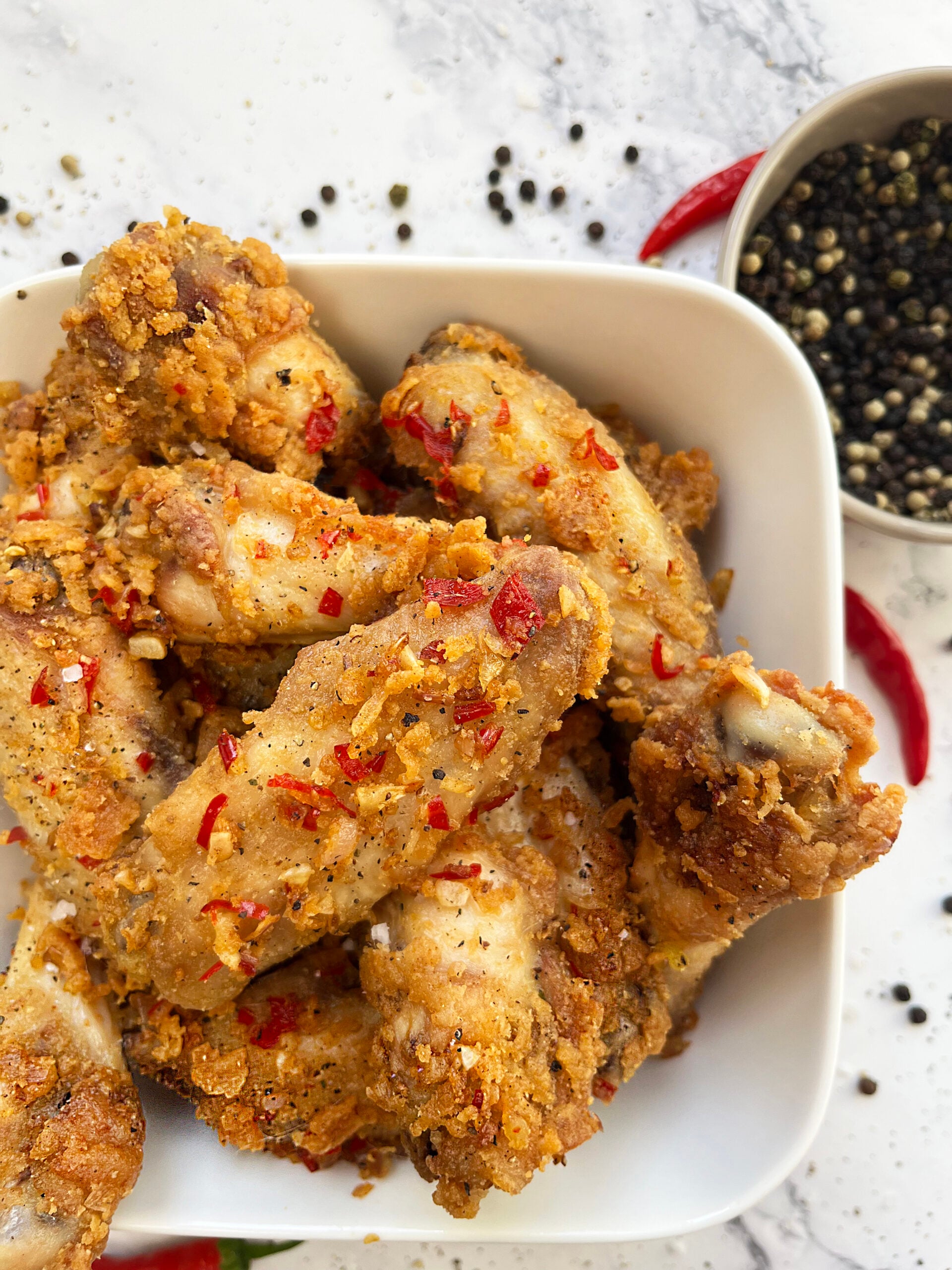 Golden fried salt and pepper chicken wings topped with red chile and pepper.