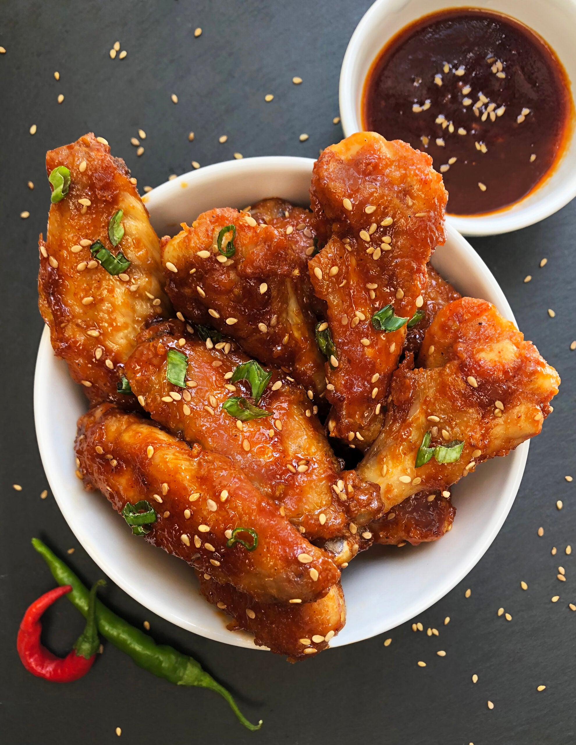 Sticky gochujang chicken wings served with extra sauce, sesame seeds and green onions.