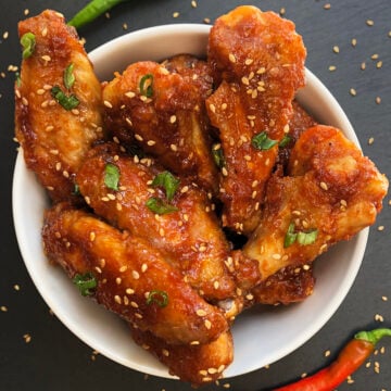 Sticky baked gochujang chicken wings with sesame seeds and green onions.