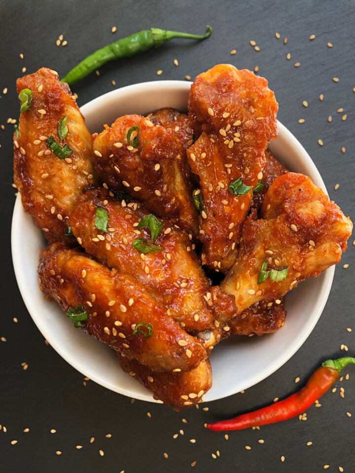 Sticky baked gochujang chicken wings with sesame seeds and green onions.