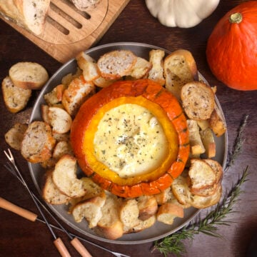 Pumpkin Brie fondue surrounded by toasted baguette slices and fresh rosemary.