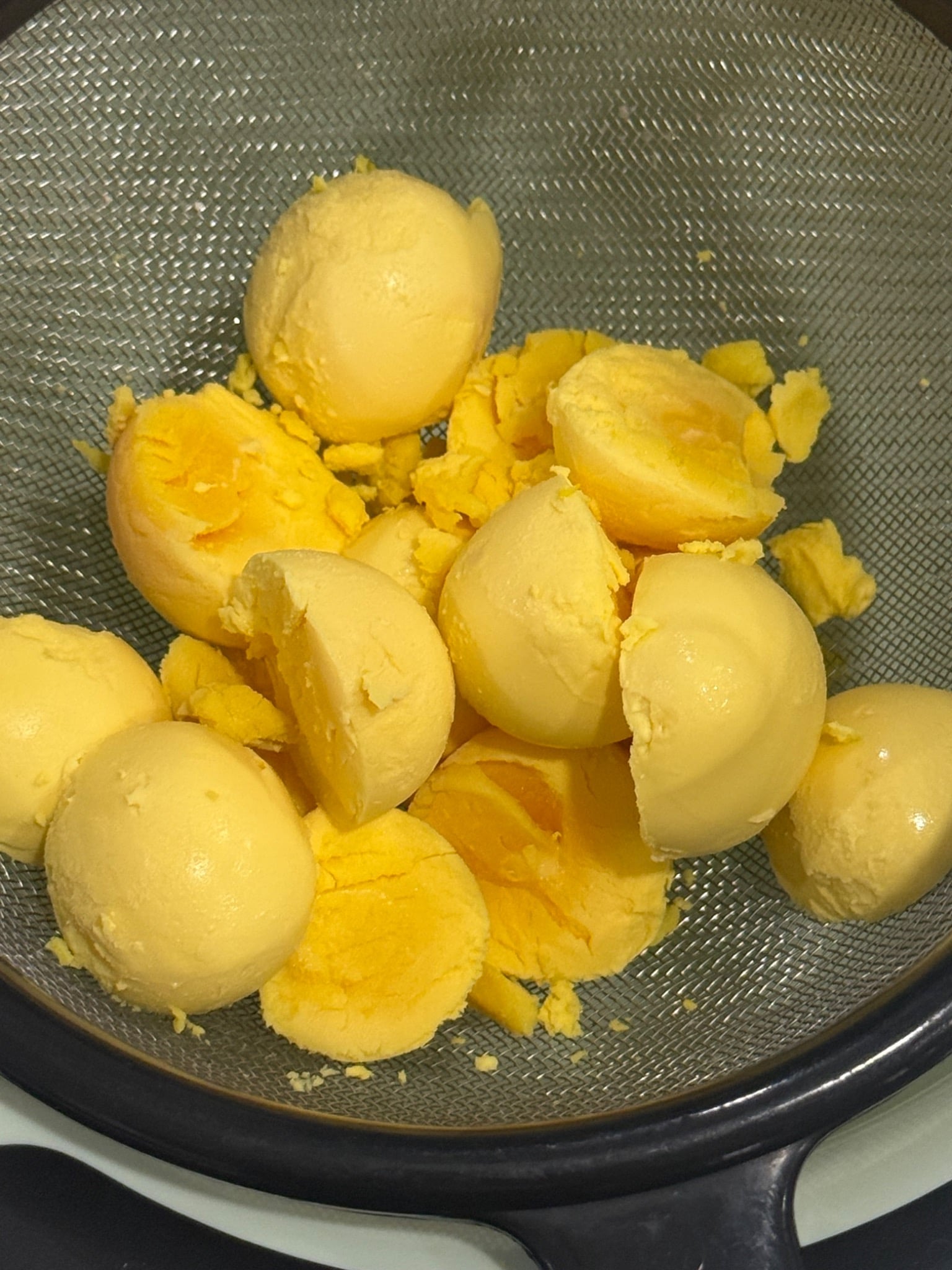 Cooked egg yolks in a fine-mesh sieve before pressing